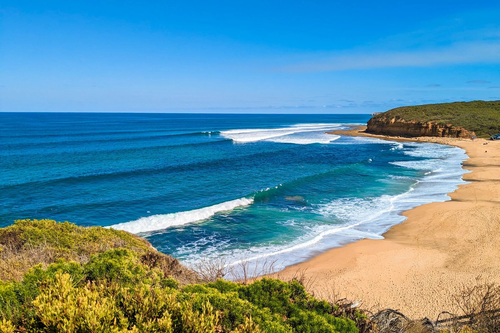 A golden Surf Coast beach near Torquay with rolling waves and coastal cliffs